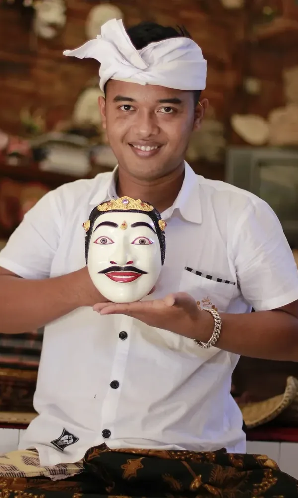 Komang Mega, a mask maker holding one of his carved masks